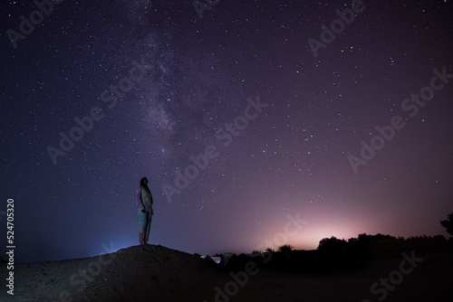 Milky Way. Night sky with stars and silhouette of a standing happy person with yellow and blue light. Space background, Astro photography 