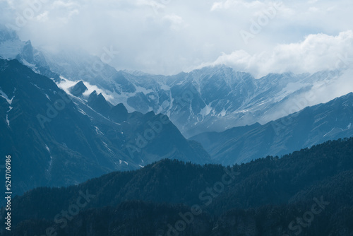 Snow covered Himalayan mountain range with clouds rolling over peaks during winter in Manali, Himachal Pradesh, India. Indian travel destination. Winter mountain landscape