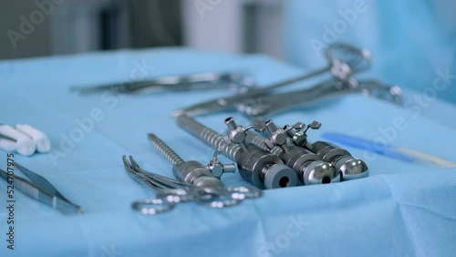 New samples of medical bipolar laparoscopic clamps (scissors) of various types and purposes in the operating room. Laparoscopic scissors and graspers on blue desk. photo