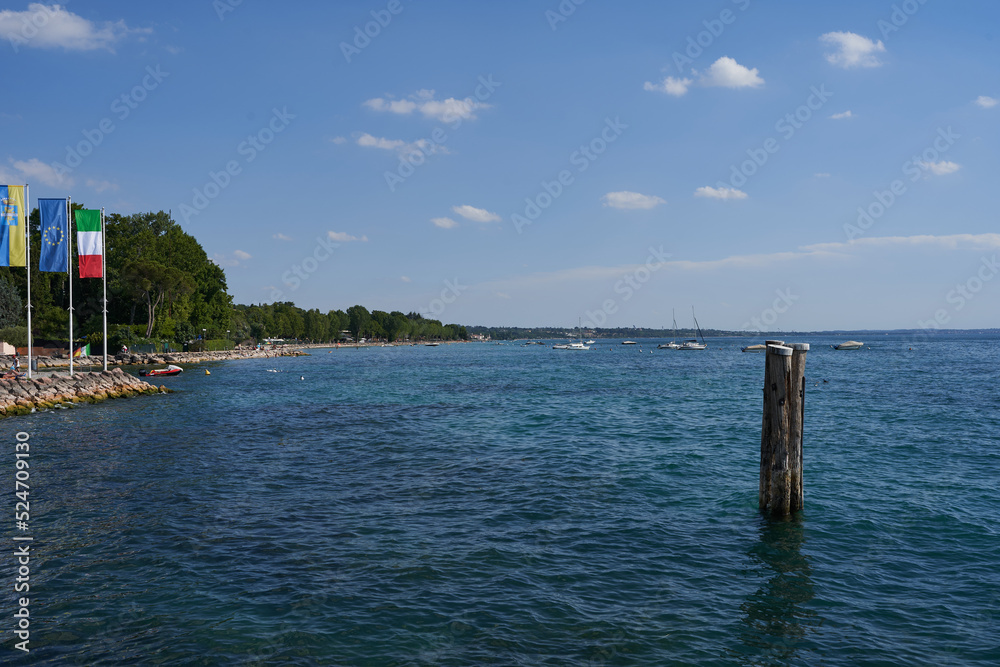 The clear blue water of Lake Garda with wooden stake on a summer afternoon