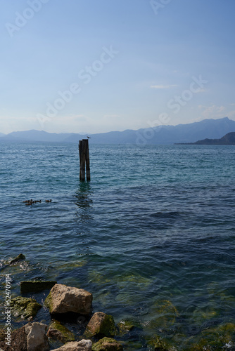 The clear blue water of Lake Garda with wooden stake on a summer afternoon