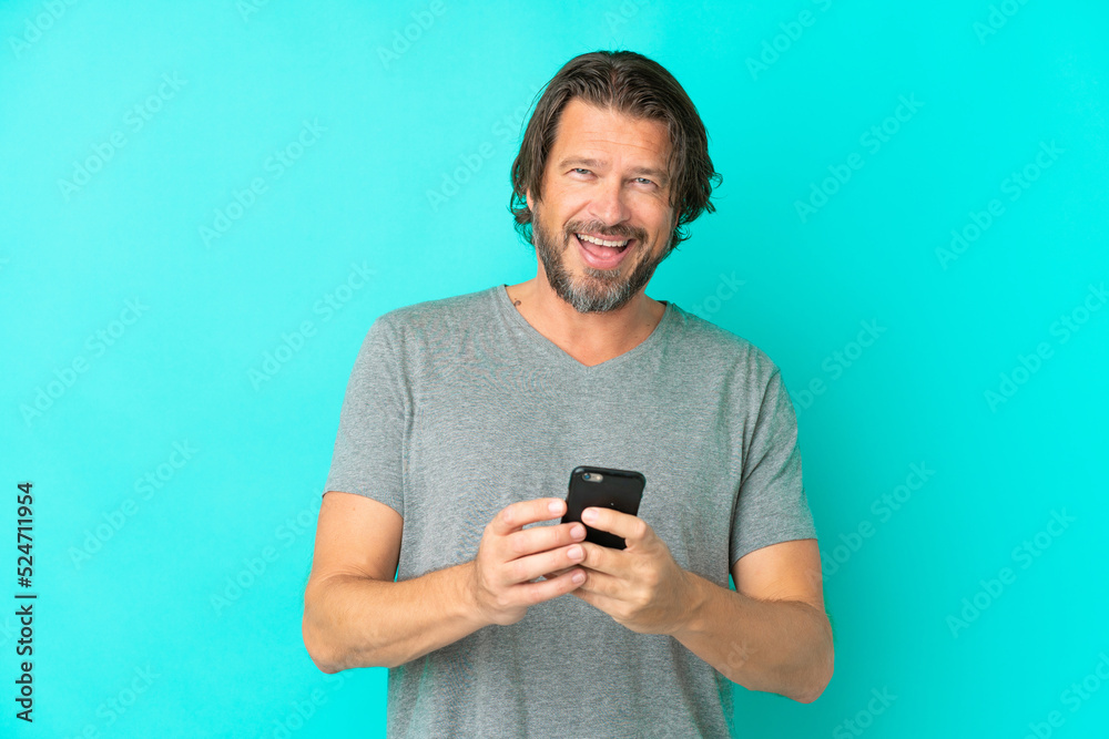 Senior dutch man isolated on blue background surprised and sending a message Senior dutch man isolated on blue background surprised and sending a message