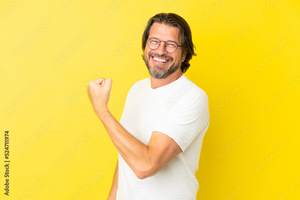 Senior dutch man isolated on yellow background doing strong gesture Senior dutch man isolated on yellow background doing strong gesture