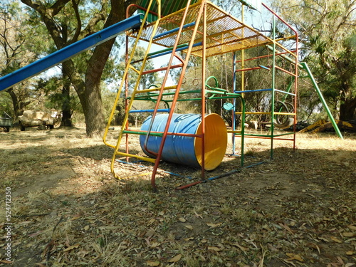 Colorful Children Jungle Gym with a blue slide and green roof outside a cottage on a farm under trees, in Gauteng, South Africa