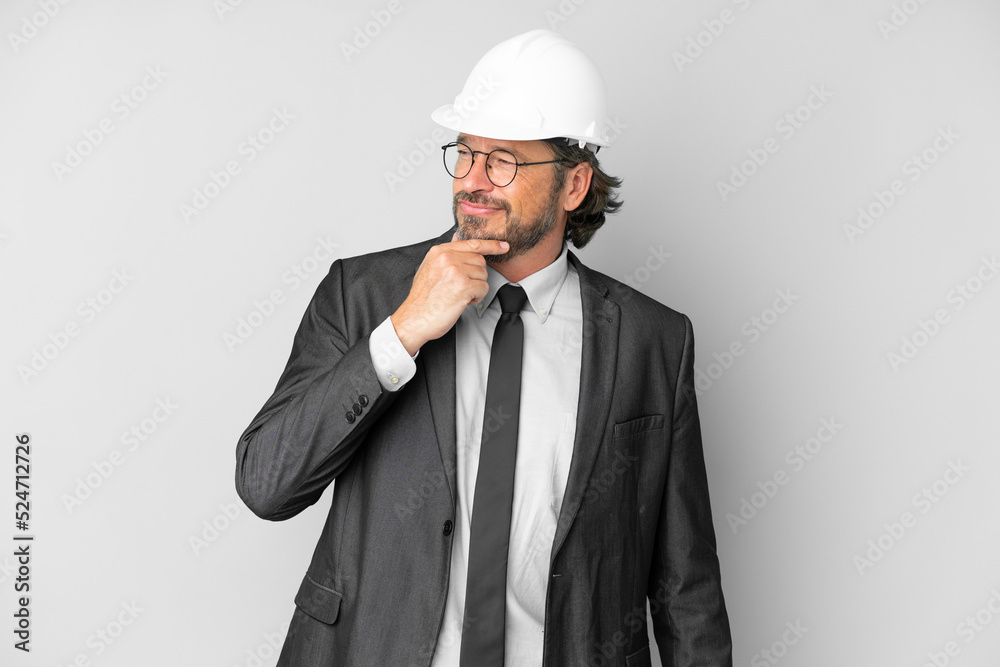 Young architect man with helmet over isolated background looking to the side