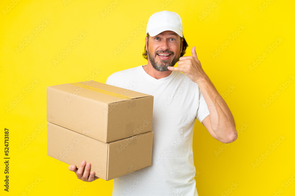 Delivery senior dutch man isolated on yellow background making phone gesture. Call me back sign Delivery senior dutch man isolated on yellow background making phone gesture. Call me back sign