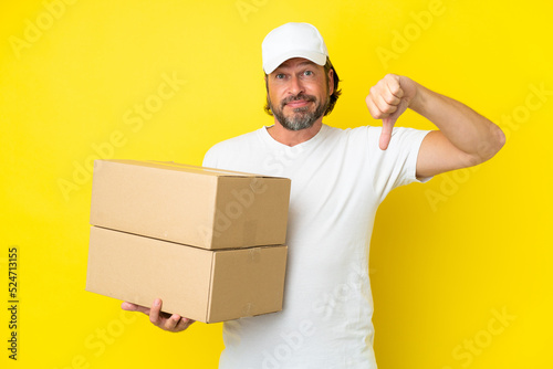 Delivery senior dutch man isolated on yellow background showing thumb down with negative expression