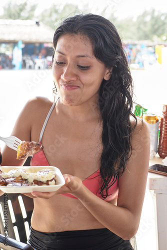 young latin woman with dark skin eating typical local dish photo