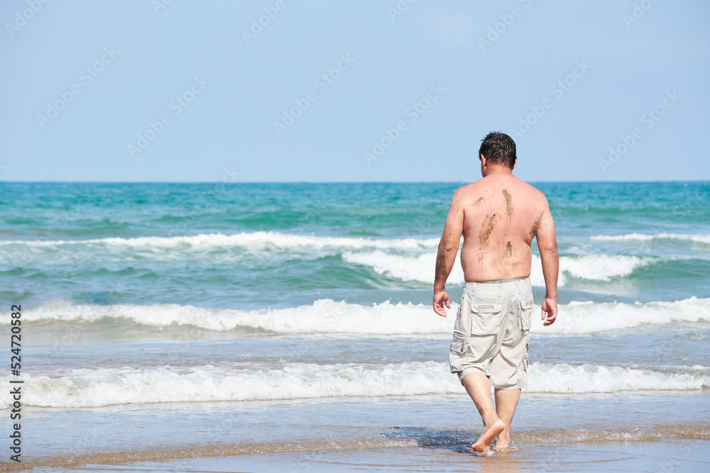 adult latin man walking on the beach