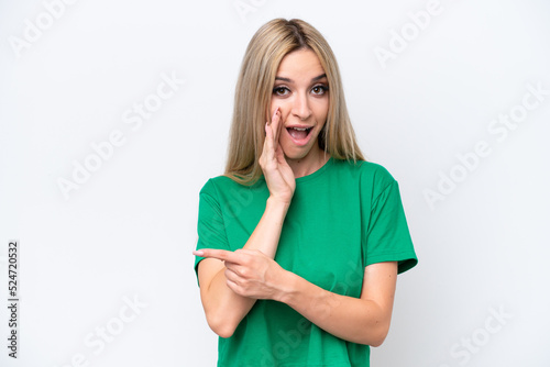 Pretty blonde woman isolated on white background pointing to the side to present a product and whispering something