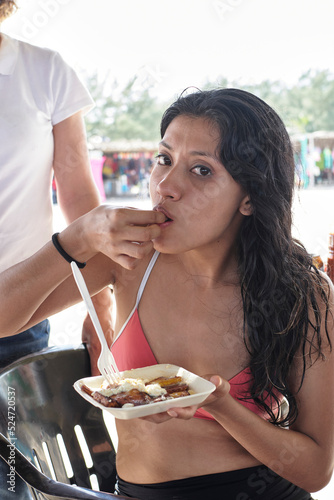 young latin woman with dark skin eating typical local dish