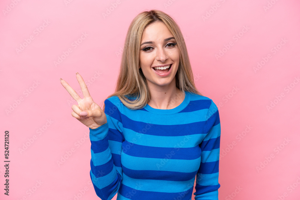 Pretty blonde woman isolated on pink background smiling and showing victory sign Pretty blonde woman isolated on pink background smiling and showing victory sign