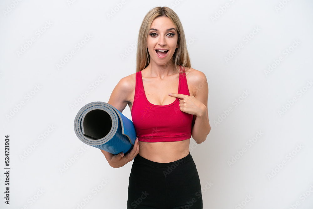 Young sport blonde woman going to yoga classes while holding a mat isolated on white background with surprise facial expression