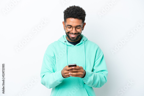 Young Brazilian man isolated on white background sending a message with the mobile