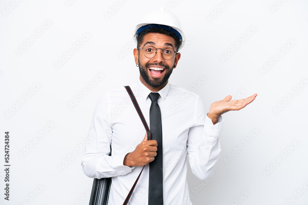 Young architect Brazilian man with helmet and holding blueprints isolated on white background with shocked facial expression