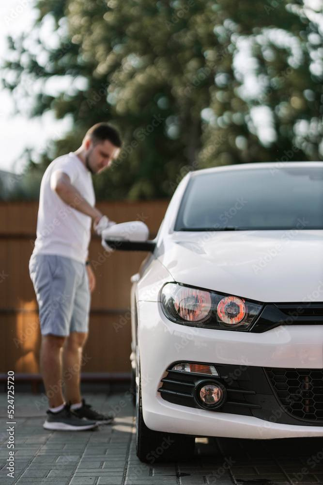 Man is wiping the car with a microfiber cloth. Contactless self-service car wash. Personal car care cleaning outside. Concept disinfection and antiseptic cleaning of vehicle, covid-19 and coronavirus Man is wiping the car with a microfiber cloth. Contactless self-service car wash. Personal car care cleaning outside. Concept disinfection and antiseptic cleaning of vehicle, covid-19 and coronavirus