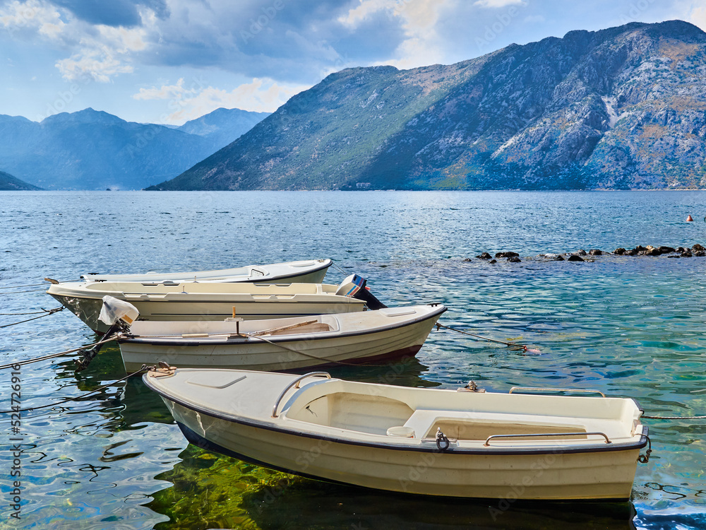 Beautiful landscape of Kotor bay, Boka Kotorska, and the Dinaric Alps. Four white boats in Dobrota, Adriatic sea, Montenegro, Europe