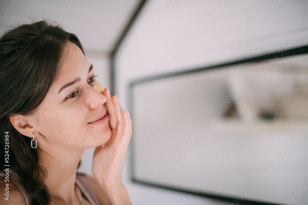 Young woman with patches under her eyes at the mirror at home. Young woman with patches under her eyes at the mirror at home.