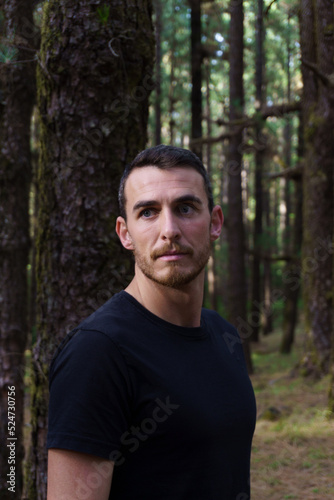 Retrato hombre blanco con camiseta negra en el bosque