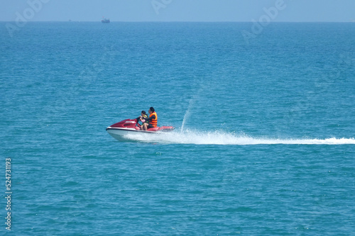  2 persons drive on the jet ski on blue sea water in summer sunny day. Vacation near the sea, travelling concept