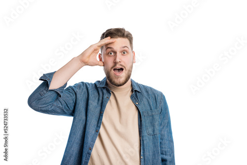 Excited young male with hand on face feeling astonished while looking straight. Portrait of emotional man with wide open eyes and mouth in white studio.