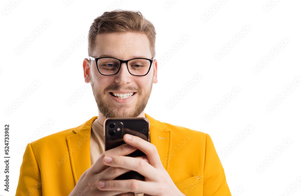 Happy stylish man with modern smartphone in hands surfing internet or texting messages while standing in studio. Concept of people and gadgets. Happy stylish man with modern smartphone in hands surfing internet or texting messages while standing in studio. Concept of people and gadgets.
