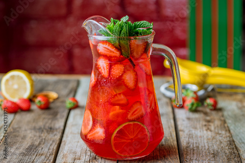 Strawberry lemonade with lime on wooden table side view photo