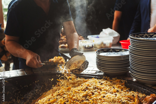 uzbek imposes the national dish "pilaf" in uzbekistan. preparation for dinner in a tourist place in tashkent. packing rice on plates in tashkent