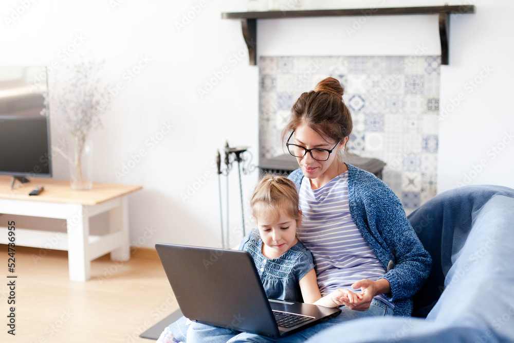 Mother and daughter using laptop at home office. Woman and child in virtual school class. Freelancer workplace for female business, working mom, homeschooling, online education. Technology lifestyle Mother and daughter using laptop at home office. Woman and child in virtual school class. Freelancer workplace for female business, working mom, homeschooling, online education. Technology lifestyle