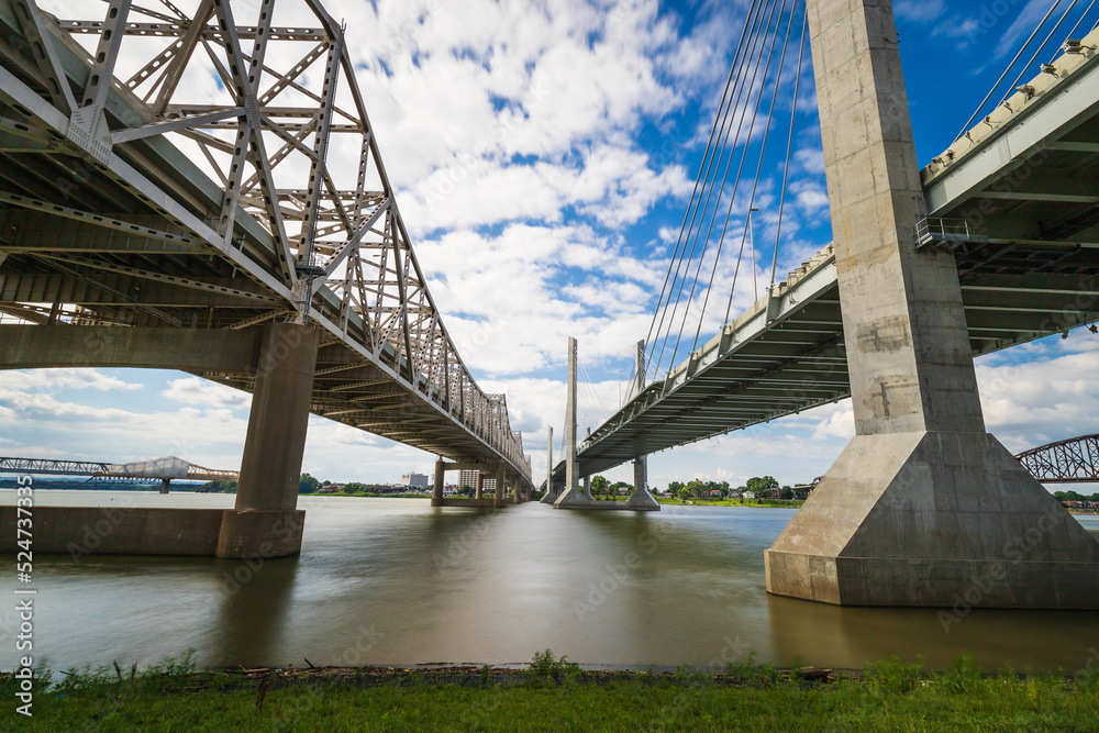 Obraz premium The Abraham Lincoln Bridge and John F. Kennedy Memorial Bridge crossing the Ohio River from Kentucky to Indiana. Long exposure sky and water movement.