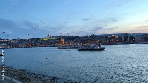 Danube River with a ship in the evening flies a lot of crows and pigeons in the distance bridge in the evening very beautiful all in blue 03.04.22 Danube Hungary. High quality 4k footage photo