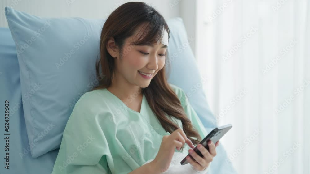 Portrait of young patient woman in hospital. She using smartphone with smiling at hospital room. Portrait of young patient woman in hospital. She using smartphone with smiling at hospital room.
