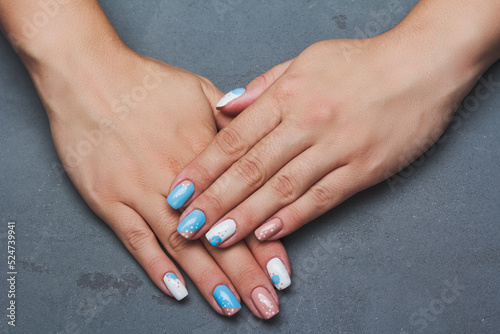 Geometry nail art design in white and blue colors on grey background