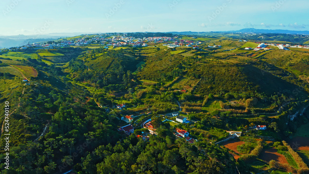 Top view of a European town with beautiful green landscape during sunset. Drone view of a beautiful small European city with a beautiful hilly landscape while sunset.  Portugal.