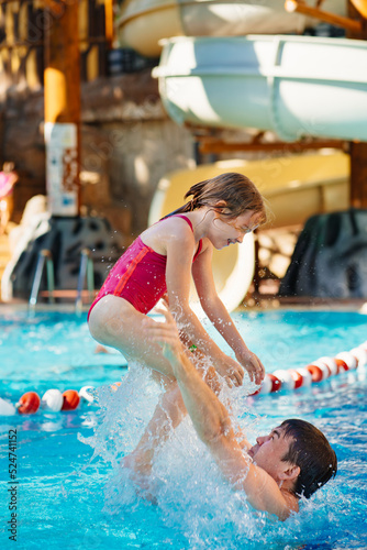 dad throws up his daughter, they have fun and play together in the pool.  © andrey