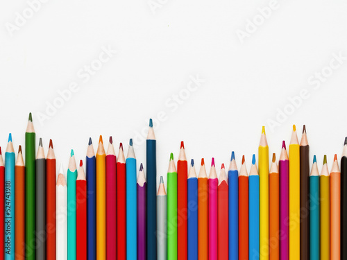Row of colorful watercolor pencils. School supplies on light paper background. Top view on kid's stationery. Back to school. White background with copy space.
