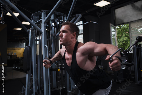 Focused muscular bodybuilder working out in crossover gym machine