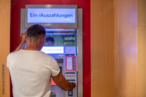 Mann hebt Geld am Bankautomaten ab