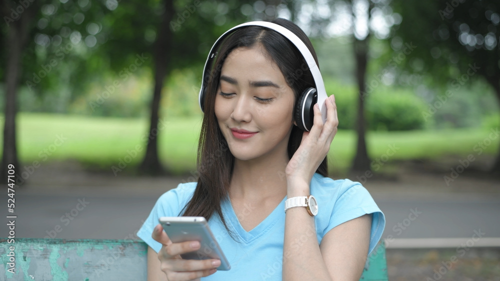 Holiday concept of 4k Resolution. Asian woman enjoying listening to music in the park. Holiday concept of 4k Resolution. Asian woman enjoying listening to music in the park.