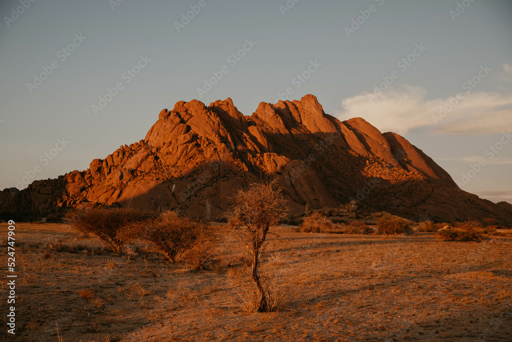 sun setting on red rock mountains in namibia desert