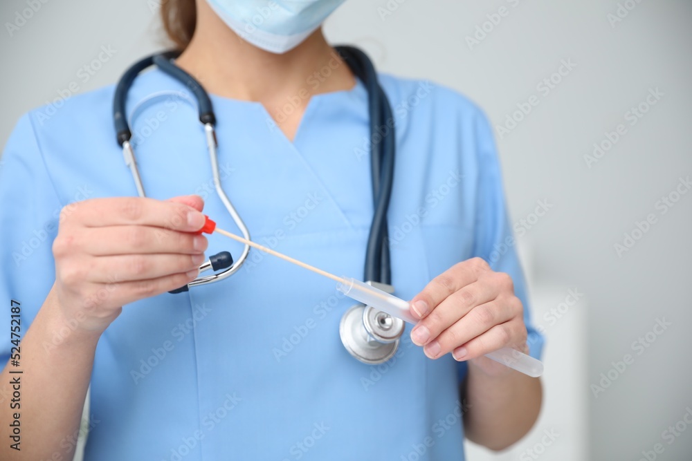 Doctor holding buccal cotton swab and tube for DNA test in clinic, closeup Doctor holding buccal cotton swab and tube for DNA test in clinic, closeup