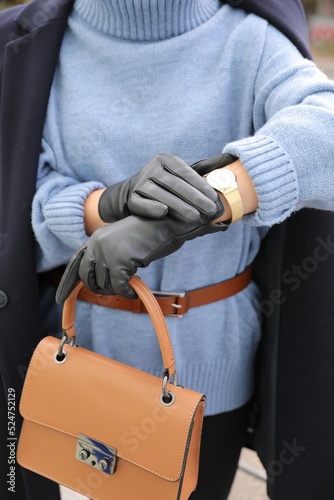 Young woman with stylish black leather gloves and bag outdoors, closeup