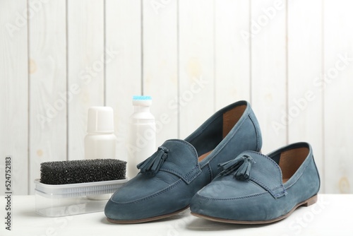 Stylish footwear with shoe care accessories on white table