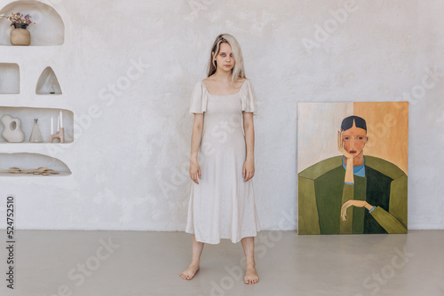 Girl in a linen dress and dried flowers near a white wall