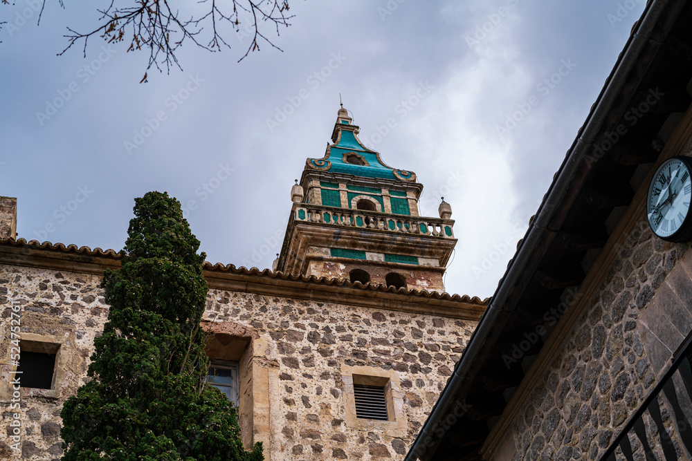 View of the beautiful blue tower of the Valldemossa charterhouse from below. Photograph taken in Valldemossa, Majorca, Spain. View of the beautiful blue tower of the Valldemossa charterhouse from below. Photograph taken in Valldemossa, Majorca, Spain.