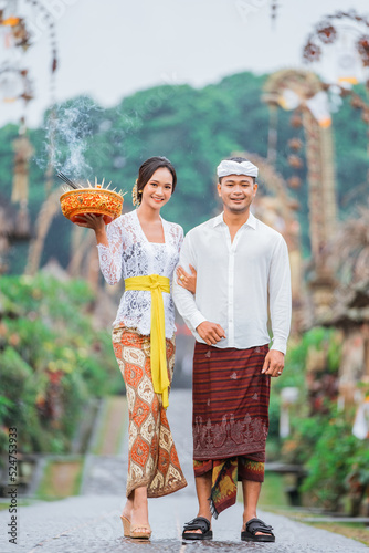 balinese couple walking in pengelipuran village wearing kebaya or traditional costume photo