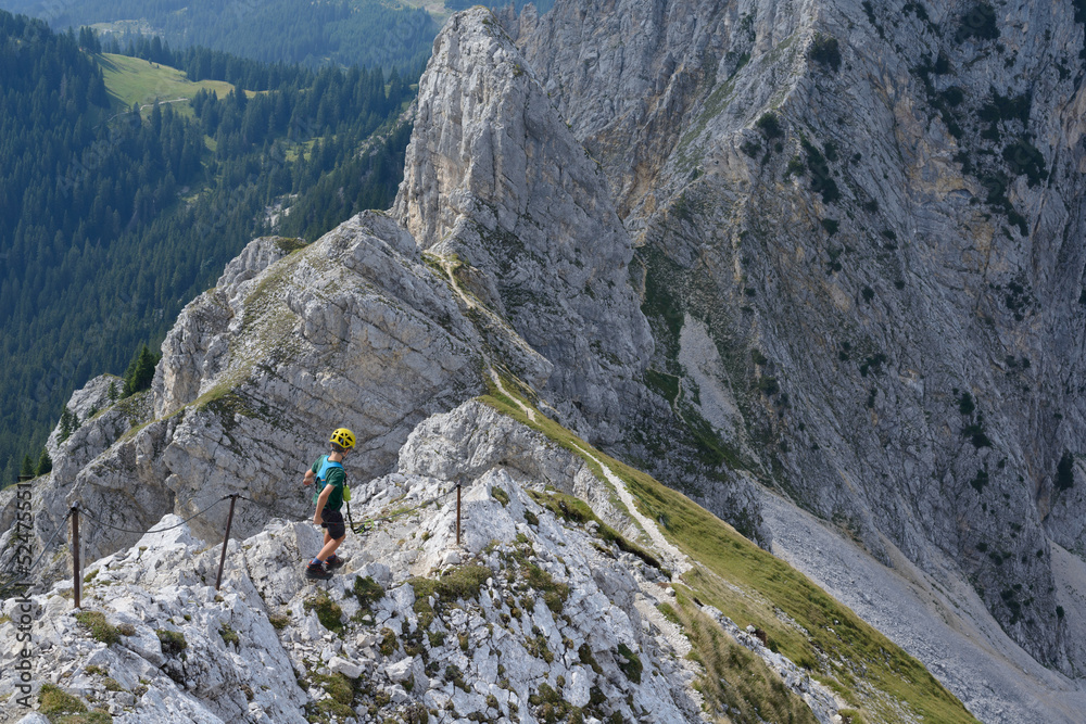 Ten-year-old boy secures himself with via ferrata set on a rocky ridge