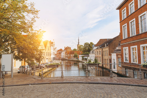 Scenic city view of Bruges canal with beautiful medieval colored houses, bridge and reflections in the evening gold hour, Belgium