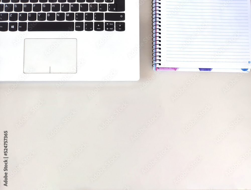 Simple and clean image showing white Laptop and white notebook on the white office table with blank space to write Simple and clean image showing white Laptop and white notebook on the white office table with blank space to write
