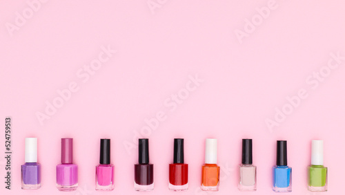Colorful nail polish bottles on pastel pink background. Flat lay copy space